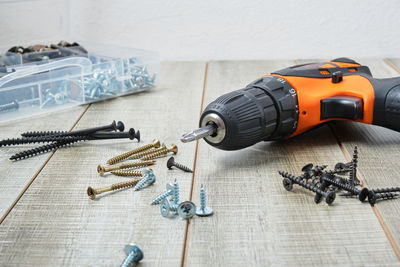 Electric screwdriver, self-tapping screws, screwdriver bits, tool box on a wooden background 