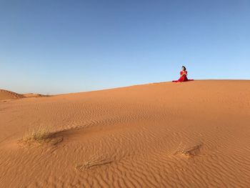 Young woman on sand at beach against clear blue sky