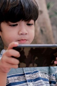 Close-up portrait of cute boy holding camera