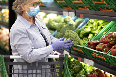 Woman wearing mask buying vegetables at supermarket