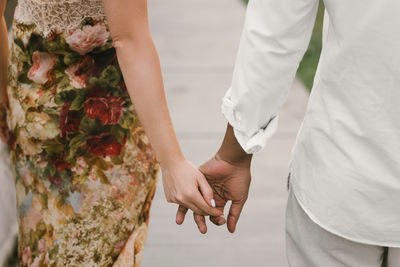 Midsection of couple holding hands
