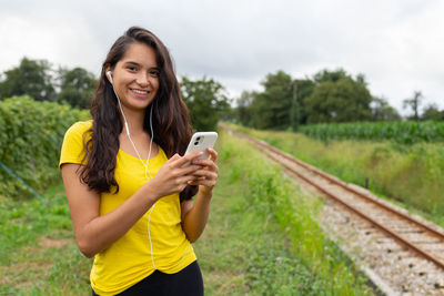 Content young ethnic lady listening to song and using smartphone in nature