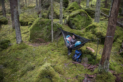 Woman sitting in hammock in forest