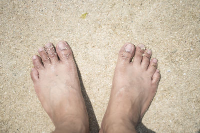 Low section of person standing on sand