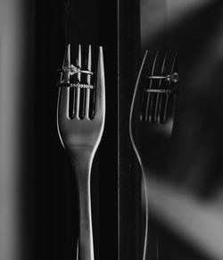 Close-up of wedding rings on fork with window reflection