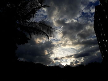 Low angle view of silhouette trees against storm clouds