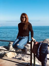 Portrait of young woman looking at sea against clear sky