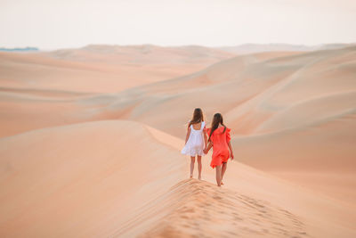 Rear view of women walking in desert