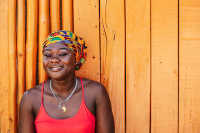 African woman with a hopeful happy smile standing against a painted wooden wall