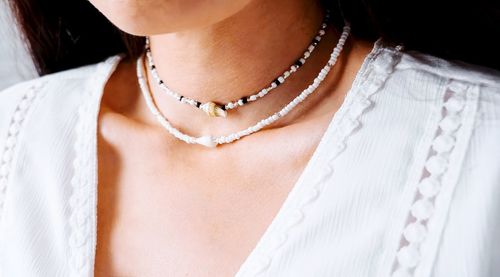 Brunette girl in a white lace blouse and a beaded and shell jewelry on her neck