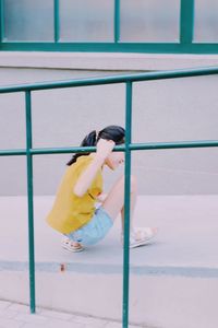 Girl crouching by railing