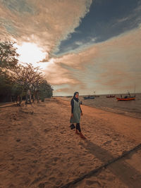 Rear view of woman walking on beach during sunset