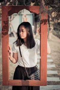 Portrait of young woman standing by railing