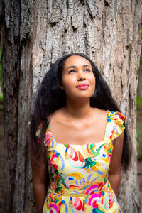 Portrait of woman standing against tree trunk