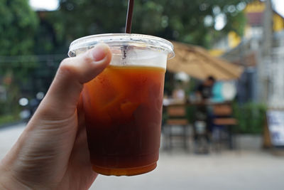 Close up hand holding iced black coffee