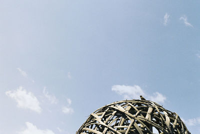 Low angle view of bird perching on structure against sky