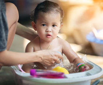 Mother bathes the kid concept. adorable girl in bathtub with fluffy soap bubble. mom bathing infant. 