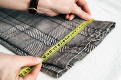 Cropped hands of man measuring fabric on table