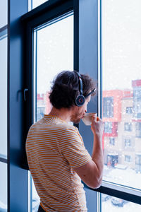 Rear view of woman looking through window