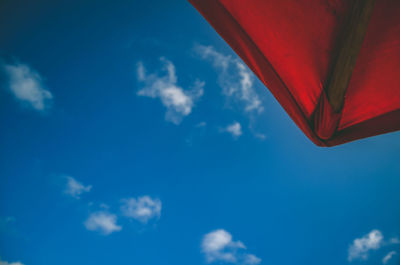 Low angle view of red umbrella against blue sky