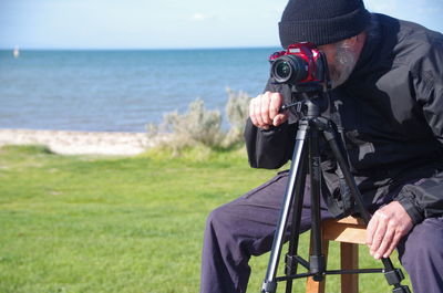 Rear view of man photographing on beach
