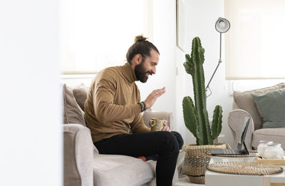 Young man sitting on sofa at home