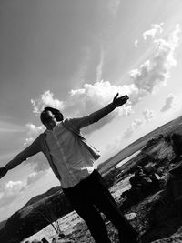 Low angle view of man with arms outstretched against sky