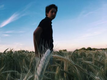 Man standing in field against sky during sunset