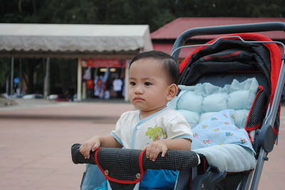 Cute baby boy looking away while sitting in stroller