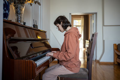 Side view of young woman playing piano
