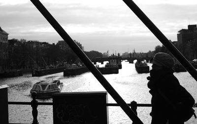 Woman by river in city against sky