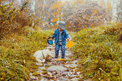 Full length of boy with dog against trees