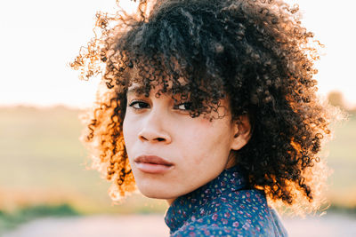 Portrait of teenage girl with curly hair during sunset