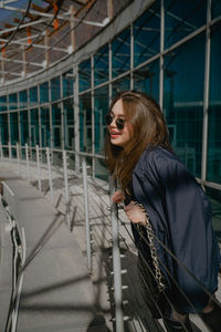 Portrait of smiling young woman standing against fence