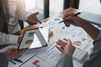 Midsection of business people working on table