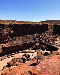 Rear view of person walking on rock against sky
