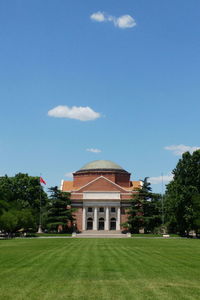 Lawn by building against blue sky