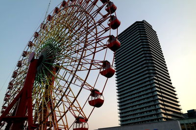 Low angle view of ferris wheel against buildings in city