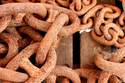 Directly above view of rusty metallic chain on wooden table