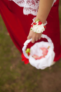 Low section of woman holding red flower