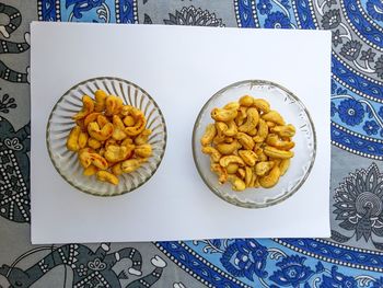 Directly above view of roasted cashews in glass bowls on paper at home