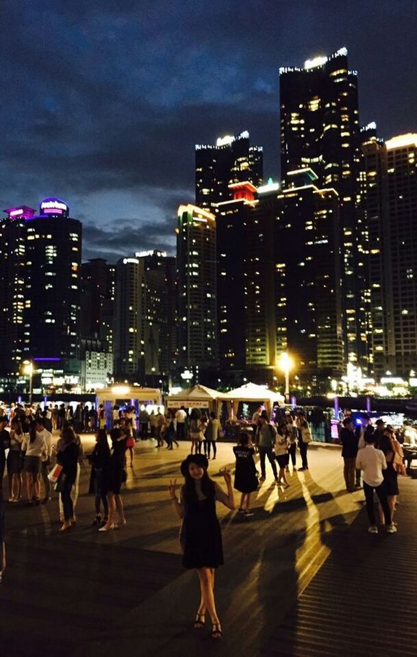 building exterior, city, architecture, illuminated, built structure, night, city life, skyscraper, large group of people, sky, men, tall - high, street, lifestyles, cityscape, office building, person, modern, tower