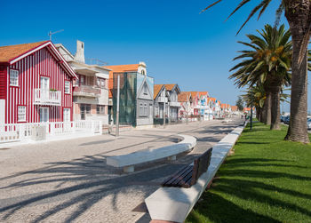 Road by houses against blue sky