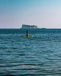 Scenic view of sea against clear sky with a lady on a raft