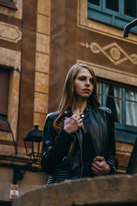 Beautiful young woman standing against wall