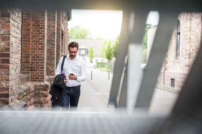 Walking businessman looking at cell phone