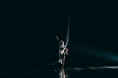 Low angle view of person standing on umbrella against black background