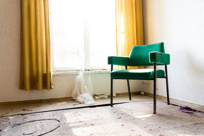 Green chair by window in abandoned building