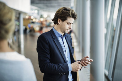 Businessman using mobile phone at airport