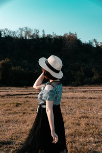 Full length of woman wearing hat standing on field